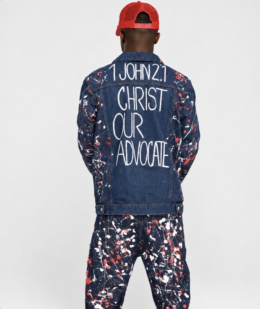 The back of the hand-painted denim jacket, hand-lettered 1 John 2:1 — Christ Our Advocate